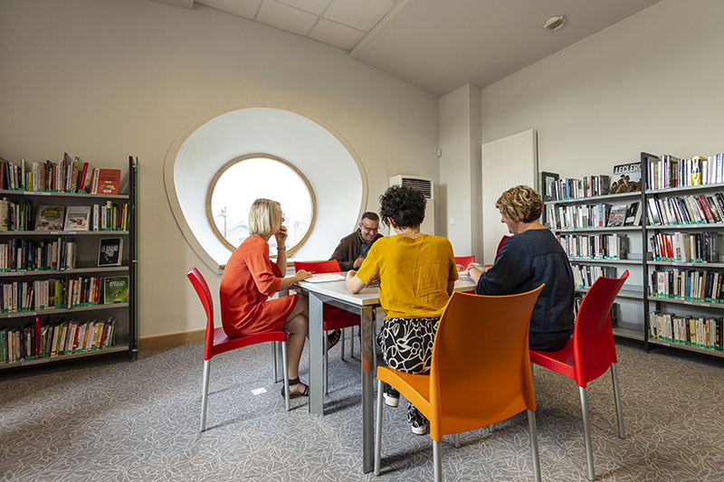 quatre personnes assises autour d'une table dans une bibliothèque