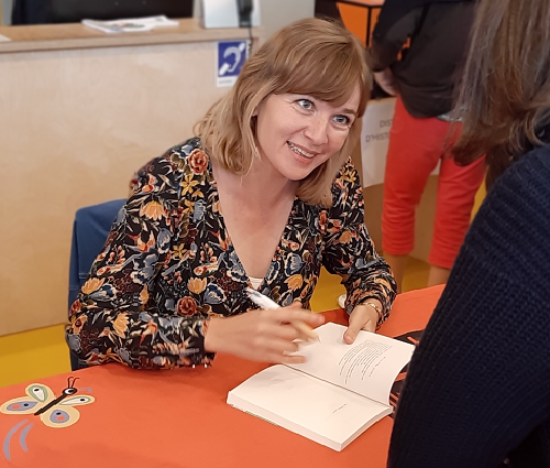 photographie de Marion Fayolle dédicaçant un livre