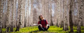 femme assise dans une clairière entourée d'arbres